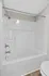 Sleek modern bathroom featuring a pristine white bathtub with chrome fixtures, showcasing contemporary style and comfort.