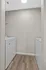Modern laundry room with sleek washer and dryer against neutral walls, featuring elegant wood-look flooring.