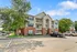 Charming apartment complex featuring three stories, lush greenery, and ample parking with a sunny sky backdrop.