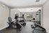 Bright and inviting apartment fitness room featuring modern exercise equipment and large windows highlighting natural light.