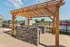 Chic outdoor area featuring a wooden pergola over a stylish stone barbecue island, perfect for entertaining.