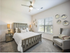 Inviting bedroom with stylish decor, featuring a cozy bed, modern lamps, elegant armchair, and artistic wall accents, bathed in natural light.
