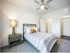 Inviting bedroom with a comfortable bed, stylish bedding, cozy lamp, and modern ceiling fan, offering a warm and relaxing atmosphere.