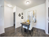 Modern dining area with elegant table setup, chic wall art, and warm wood flooring, exuding contemporary charm.