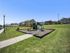 Charming apartment complex with lush green lawns and modern playground facilities under a clear blue sky.
