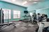 Modern and vibrant fitness center equipped with treadmills, weight machines, and free weights against a fresh blue backdrop for an energizing workout experience.