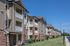 Charming apartment complex with modern design, spacious balconies, and well-maintained landscaping under a clear blue sky.