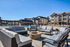 Luxurious apartment complex showcasing a spacious outdoor lounge with plush seating, a fire pit, and a sparkling swimming pool under clear blue skies.