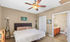 Inviting bedroom with plush bed, elegant ceiling fan, and en-suite bathroom for modern living comfort.