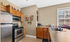 Inviting kitchen with stainless steel appliances, wooden cabinets, and a large window offering natural light.
