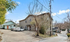 Charming suburban apartment complex with two-story buildings, ample parking space, and lush trees under a bright blue sky.