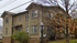 Charming two-story apartment building with rustic stone foundation, surrounded by picturesque autumn trees.