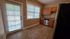 Inviting kitchen with natural light, featuring a sleek stainless steel dishwasher, wooden cabinetry, and elegant tile flooring.