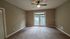 Bright, spacious room featuring plush carpeting, a contemporary ceiling fan, and French doors leading to a private balcony.