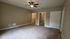 Spacious bedroom with plush carpeting, featuring a ceiling fan and a walk-in closet for convenient storage.