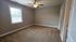 Bright, spacious bedroom with plush carpet, neutral walls, and a ceiling fan for comfort.