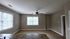 Inviting living area with large windows, abundant natural light, and modern ceiling fan.