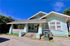 Charming bungalow with a welcoming front porch, vibrant red door, and classic architectural details, set against a clear blue sky.