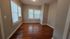 Bright and airy room with elegant hardwood floors and large windows featuring white blinds, perfect for a cozy apartment setting.