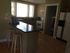 Charming kitchen with natural light, featuring a sleek granite countertop and cozy breakfast bar with wooden stools, perfect for morning coffee.
