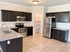 Elegant kitchen with dark wood cabinets, stainless steel appliances, and granite countertops, featuring a walk-in pantry and modern tile flooring.