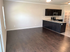 Inviting open-concept living area with elegant dark wood floors and a modern kitchen featuring sleek dark cabinetry and stainless steel appliances.