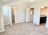 Bright, carpeted bedroom with walk-in closet and en-suite bathroom, featuring modern fixtures and ample natural light.