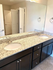Elegant bathroom vanity with dual sinks and granite countertops, highlighted by sleek fixtures and ample storage.