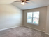 Bright and airy bedroom with plush carpet, ceiling fan, and large window offering a serene view of the neighborhood.