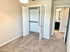 Charming and bright bedroom with plush carpet, open closet doors, and a view into a modern bathroom, offering a cozy and inviting space.