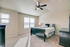 Bright and inviting bedroom with modern ceiling fan, plush carpeting, and ample natural light from large windows.