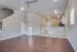 Spacious open-concept living area with elegant hardwood floors, modern ceiling fan, and a sleek kitchen with bar seating.