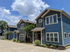 Charming row of modern blue townhouses with lush landscaping under a clear sky.