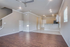 Spacious open-concept living area with elegant hardwood floors, modern ceiling fan, and a sleek kitchen with bar seating.