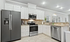 Elegant modern kitchen with sleek stainless steel appliances, white cabinetry, and ambient lighting enhancing the spacious layout.