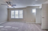 Bright and spacious bedroom with plush carpeting, modern ceiling fan, and ample natural light through large windows.