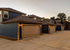 Charming row of modern townhouses with sleek garages, set against a serene evening sky.