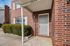 Charming brick townhouse entrance with a welcoming porch and well-maintained shrubbery.