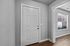 Inviting entryway with a modern white door and a sunlit room with large windows and sleek wood flooring.