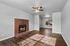 Inviting living room with a warm brick fireplace, elegant ceiling fan, and abundant natural light on stylish hardwood floors.