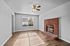 Bright living space with large window, elegant ceiling fan, and charming brick fireplace.