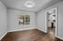 Bright and inviting room with hardwood floors and large window, offering a peek into a modern, well-equipped kitchen featuring sleek cabinetry and stainless steel appliances.