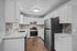 Modern kitchen with sleek stainless steel appliances, bright cabinetry, and stylish wood flooring.