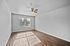 Bright and spacious room with elegant hardwood flooring, large window for natural light, and a stylish ceiling fan.