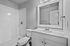 Modern bathroom with elegant subway tile shower, sleek vanity, and large framed mirror.