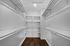 Spacious walk-in closet with ample shelving and hanging space, featuring elegant wood flooring and a sleek modern design.