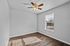 Bright, spacious room with elegant wood flooring, a ceiling fan, and large window inviting natural light.
