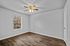 Bright and spacious room with elegant wood flooring, a ceiling fan, and a large window offering natural light.