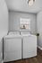Bright and spacious laundry room with modern washer and dryer, featuring natural light from a window and sleek hardwood flooring.