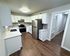 Modern kitchen with sleek stainless steel appliances, white cabinetry, and elegant wood flooring, perfect for culinary enthusiasts.